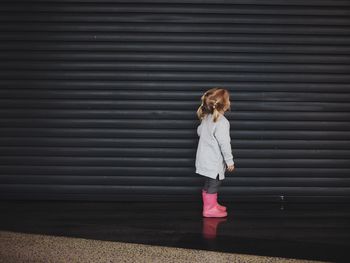 Side view of girl standing against wall