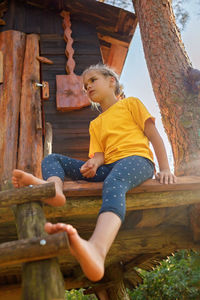 Girl plays in creative handmade treehouse in backyard, summer activity, happy childhood, cottagecore