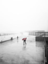 Rear view of people walking on snow against sky