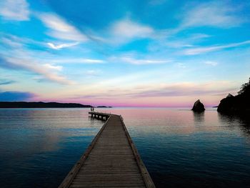 Pier over sea against sky during sunset