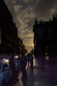 People in city against sky during sunset