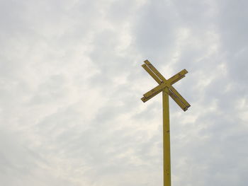 Low angle view of railroad crossing sign against sky