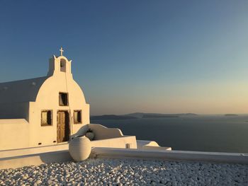 Church by sea against clear sky on sunny day