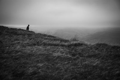 Rear view of man walking on field against sky