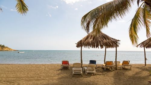 Deck chairs and thatched roof umbrella at beach