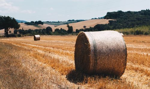 Hay bales on field against sky