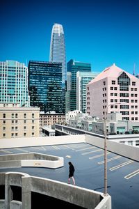 Man and modern buildings against clear blue sky