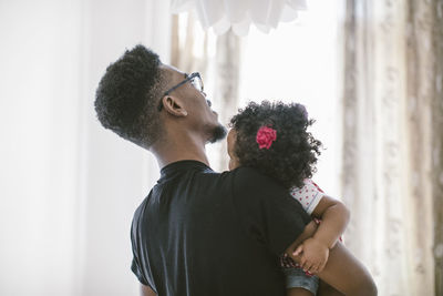 Young man carrying daughter at home