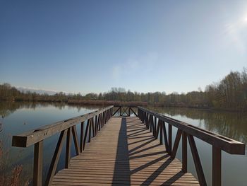 Wooden bridge over lake against sky
