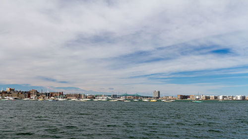 Sea by buildings against sky in city