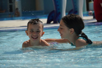 Portrait of happy brother with sister swimming in pool