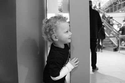 Smiling boy hiding behind column at shopping mall