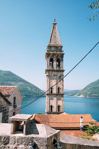 Tower of building by sea against clear blue sky