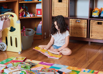 Young girl is reading a book on the floor