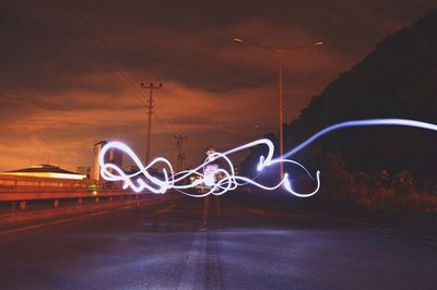 Light trails on road against sky at night