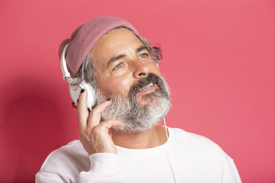 Dark gray haired middle aged man 40s 50s in casual sweater listening to music with headphones 