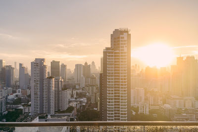 Modern buildings in city against sky during sunset