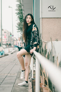 Full length portrait of woman standing against wall