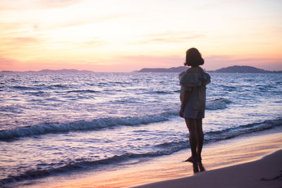 Man standing on beach against sky during sunset