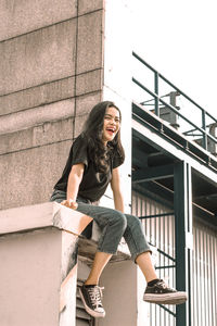 Smiling young woman sitting on building