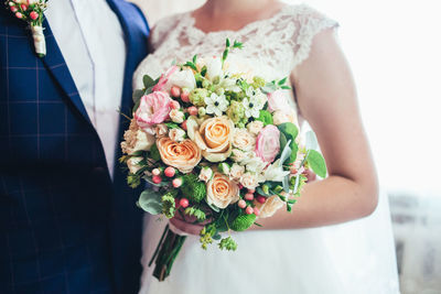 Midsection of bridal couple holding bouquet