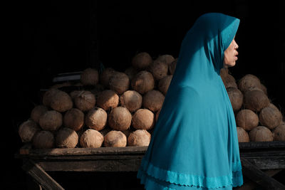 Old lady with green hijab and coconuts at the background