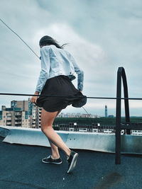 Rear view of woman standing on bridge over sea against sky