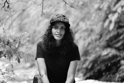 Portrait of smiling woman standing against trees