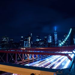 Illuminated bridge and buildings against sky at night