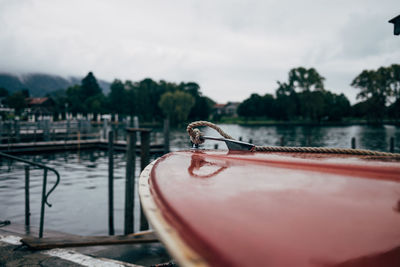 Close-up of boat moored at riverbank against sky