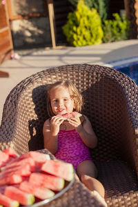 Cute girl eating watermelon while sitting outdoors