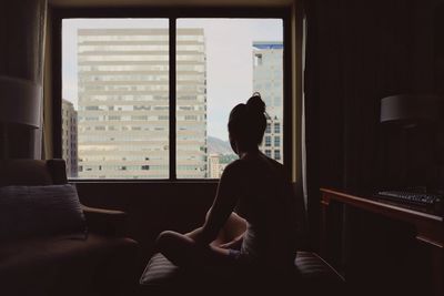 Rear view of woman sitting in hotel room