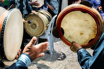 Midsection of people playing drums while standing outdoors