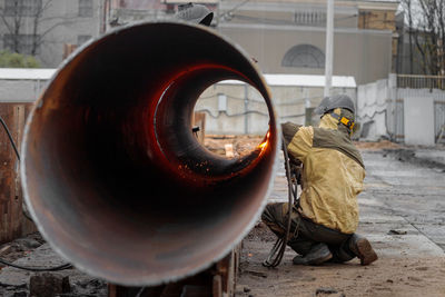 Rear view of welder welding outdoors