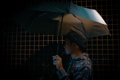 Portrait of man holding wet umbrella during rainy season