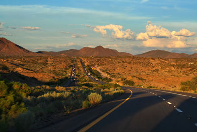 Road leading towards mountains against sky