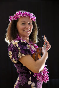 Close-up portrait of woman wearing flowers with guitar standing against wall