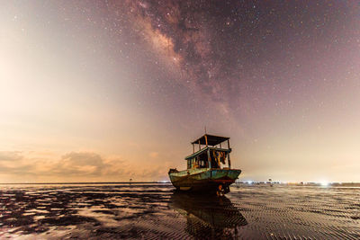 Boat moored on sea against sky at night