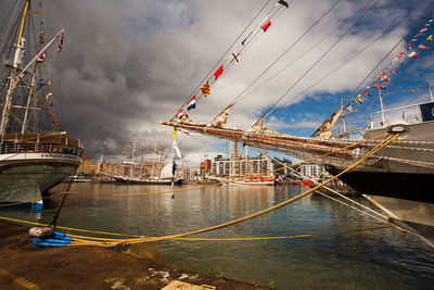 Boats moored at harbor against sky