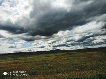 Scenic view of field against cloudy sky