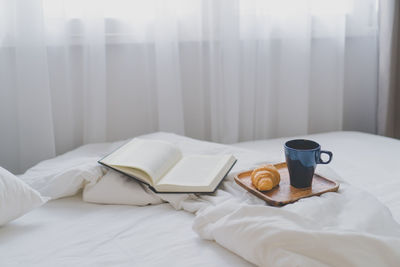 Book and crockery on bed at home