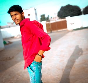 Young man standing against red wall