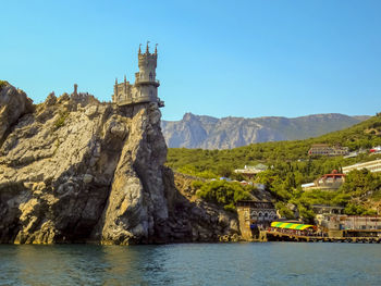 Scenic view of historic building by mountains against clear sky