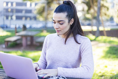 Young woman using laptop while sitting at table