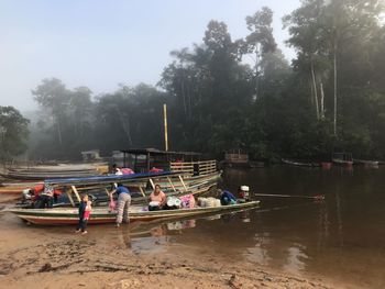 Group of people in boat on lake against trees