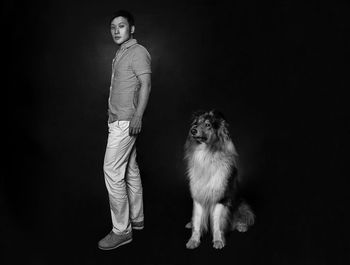 Portrait of man and dog against black background
