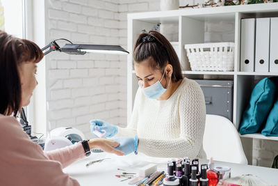 Young woman wearing glove and mask working at salon