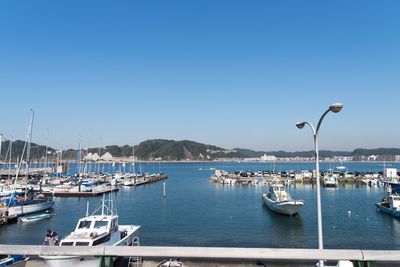 Boats moored in sea against clear blue sky