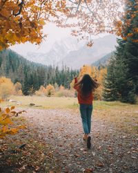 Rear view of woman standing on autumn leaves