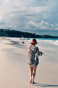 Full length rear view of woman walking on beach